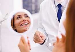 Happy patient holding mirror and looking at dentist