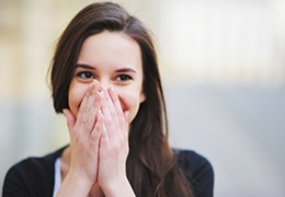 Smiling woman covering her mouth