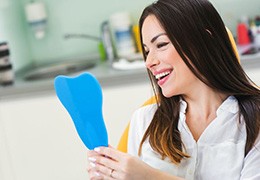 Dental patient holding mirror and admiring her smile