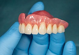 Close-up of gloved hand holding denture