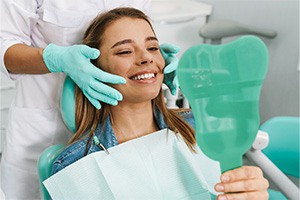 Patient smiling while holding dental mirror