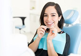 Happy female dental patient holding clear aligner